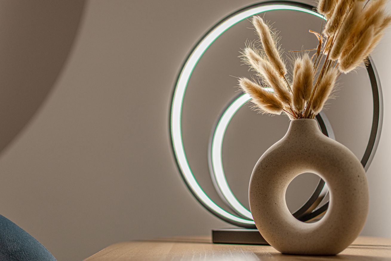 A modern vase with a circular cutout on a wooden surface.