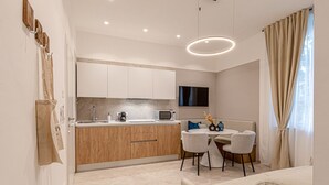A modern kitchen with wooden cabinets, a microwave, and a dining area with a table and chairs. - Eternity Apartment – Luxury in the City (Civitanova Marche)