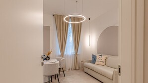 A modern living room with a round table, a sofa, and a ceiling light fixture. - Eternity Apartment – Luxury in the City (Civitanova Marche)