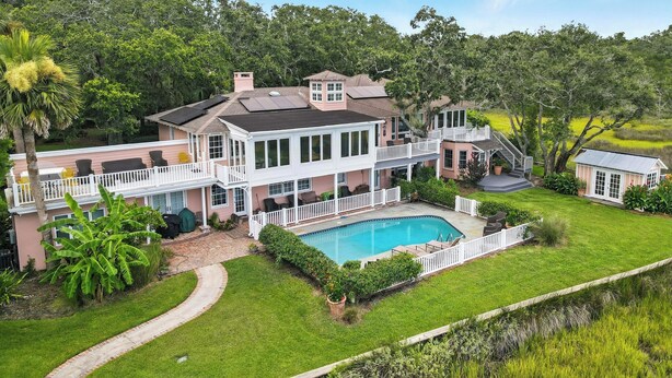 A large house with a swimming pool, multiple decks, and lush greenery. - Historic Marshfront St Simons Estate • Heated Pool • Private Dock (St Simons)