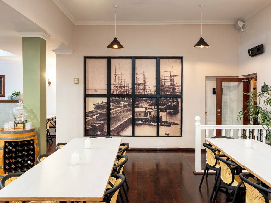 Un comedor con una larga mesa, sillas, un barril de vino y un cuadro grande en la pared.