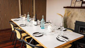 A dining table set with wine glasses, bottles, and candles, surrounded by wicker chairs.