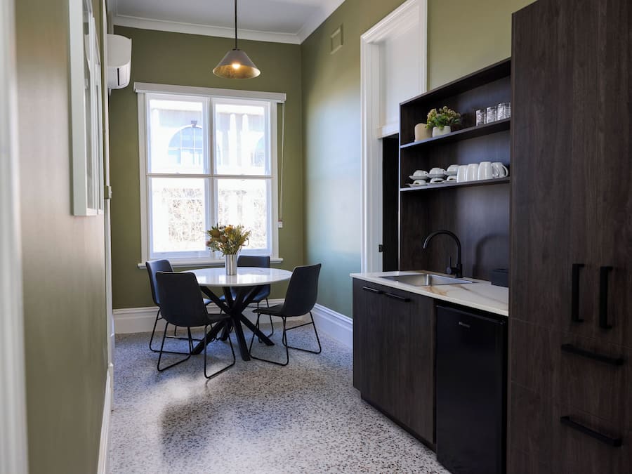 A kitchen with a round table, chairs, a sink, and cabinets.