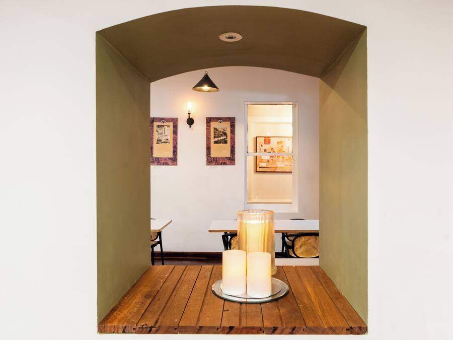 Una habitación acogedora con una mesa de madera, una vela encendida y cuadros en la pared.