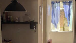 A kitchen with a refrigerator, a sink, and a window with blue curtains.