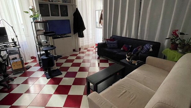 A living room with a red and white checkered floor, a beige sofa, a black coffee table, and a TV on a stand.