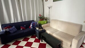 A living room with a checkered floor, two sofas, a coffee table, and a painting on the wall.