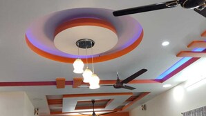 A dining area with a ceiling fan, pendant lights, and a clock on the wall. - Sarvik Residency (Tiruchirappalli)