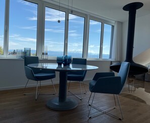Een moderne eetruimte met een ronde tafel, vier stoelen en een groot raam met uitzicht op bergen.