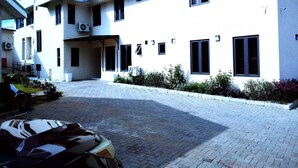 A modern building with a paved courtyard, multiple windows, and air conditioning units. - The Meridian Apartments Abuja (Abuja)
