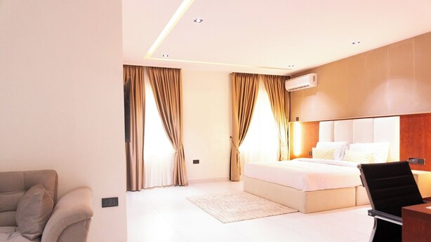 A modern hotel room with a bed, a desk, a chair, and a sofa. - The Meridian Apartments Abuja (Abuja)