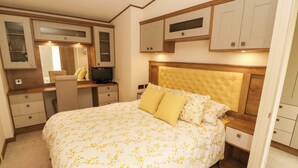 Un dormitorio con una cama grande, un escritorio, una silla, un televisor y armarios empotrados.