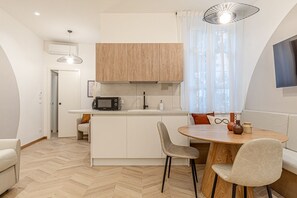 Une cuisine moderne équipée d’un four à micro-ondes, d’un évier et de meubles en bois. On y trouve également un coin repas avec une table ronde et des chaises.