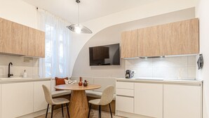 Une cuisine moderne avec une table à manger ronde, deux chaises et un téléviseur fixé au-dessus du comptoir.