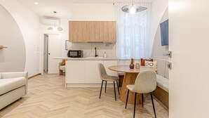 Une cuisine compacte équipée d’un four à micro-ondes, d’une machine à café et d’un coin repas avec une table ronde et des chaises.