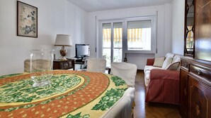 Una stanza con un tavolo da pranzo, un divano, una TV e una finestra con tende.