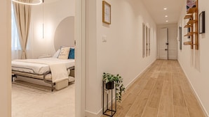 A modern hotel room with a bed, bedside table, and a potted plant.