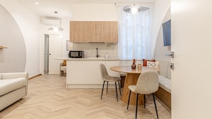 A compact kitchen with a microwave, a coffee machine, and a dining area with a round table and chairs.