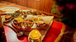 Un repas traditionnel indien, composé de différents plats et servi avec des ustensiles sur un tapis tissé.