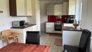 Cocina compacta con microondas, horno y lavaplatos. Hay una mesa de comedor con sillas.