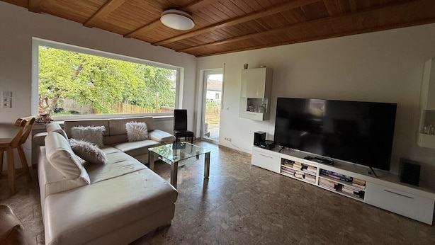 Una sala de estar con un sofá, televisor y una mesa de centro de vidrio.
