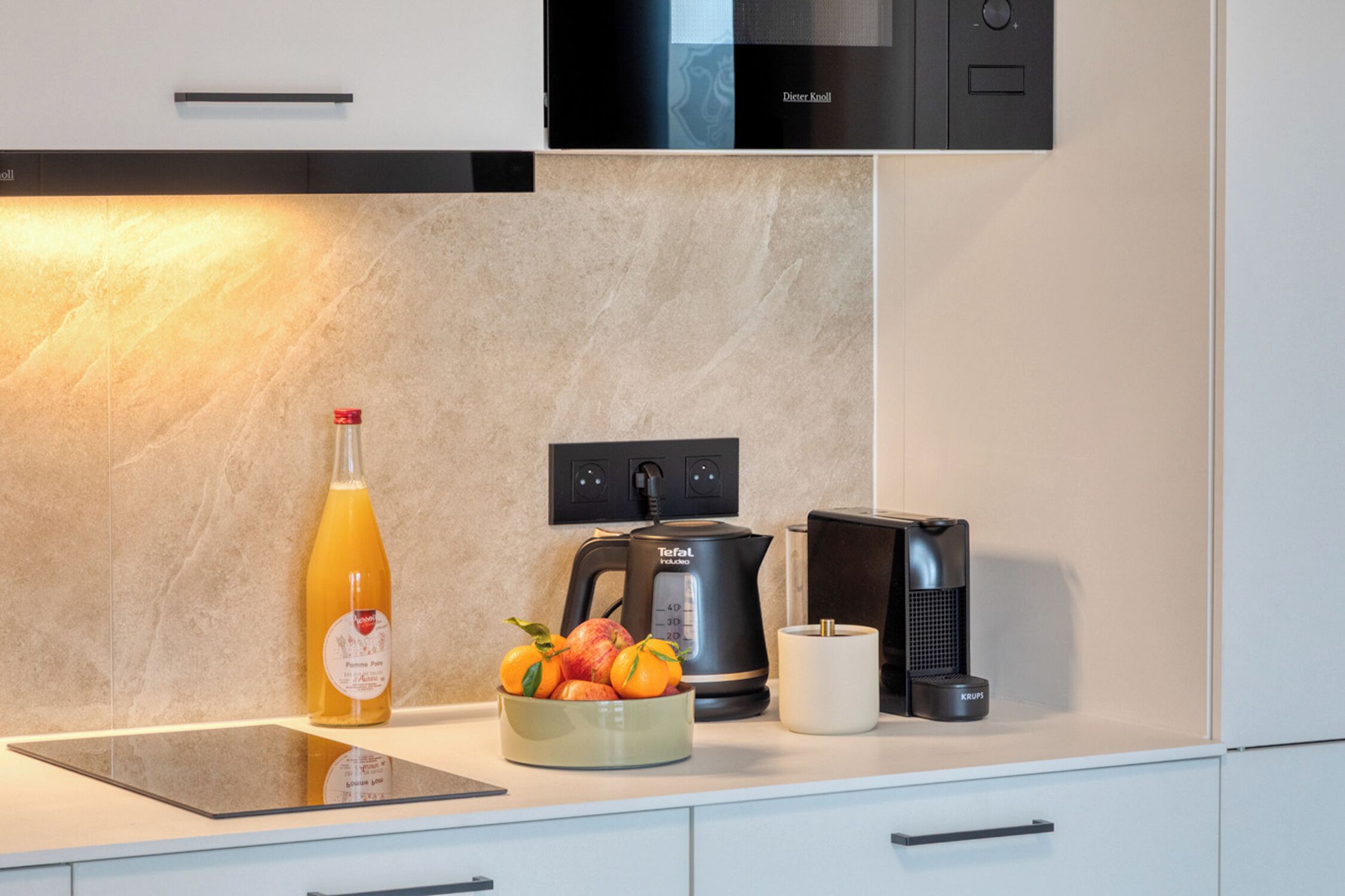 A modern kitchen with a built-in oven, a coffee machine, and a kettle.