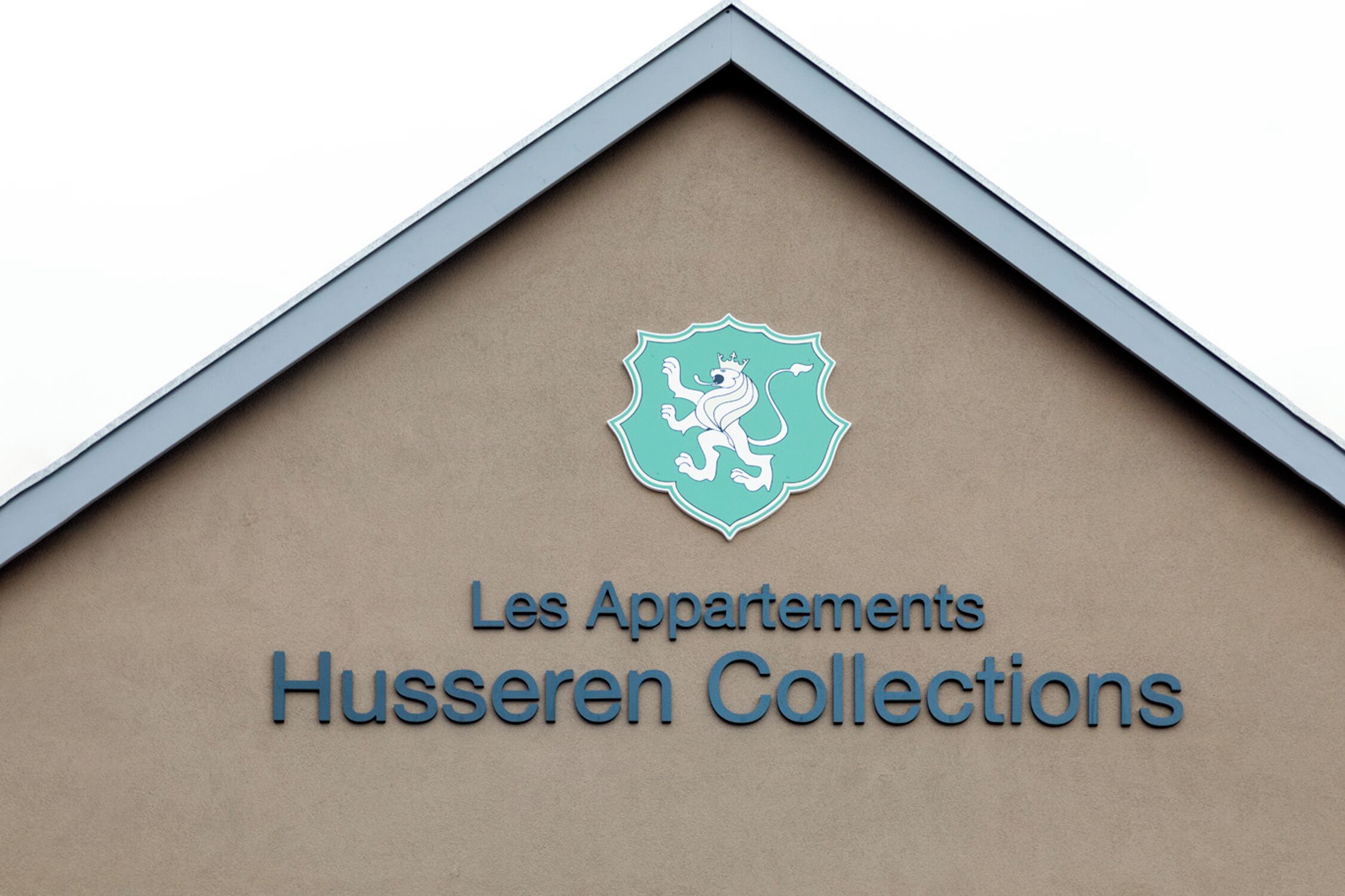 A building sign with a crest and the text "Les Appartements Husseren Collections".