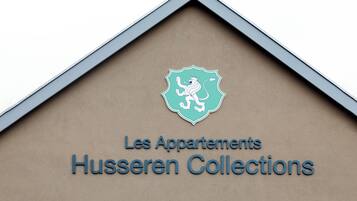 A building sign with a crest and the text "Les Appartements Husseren Collections".