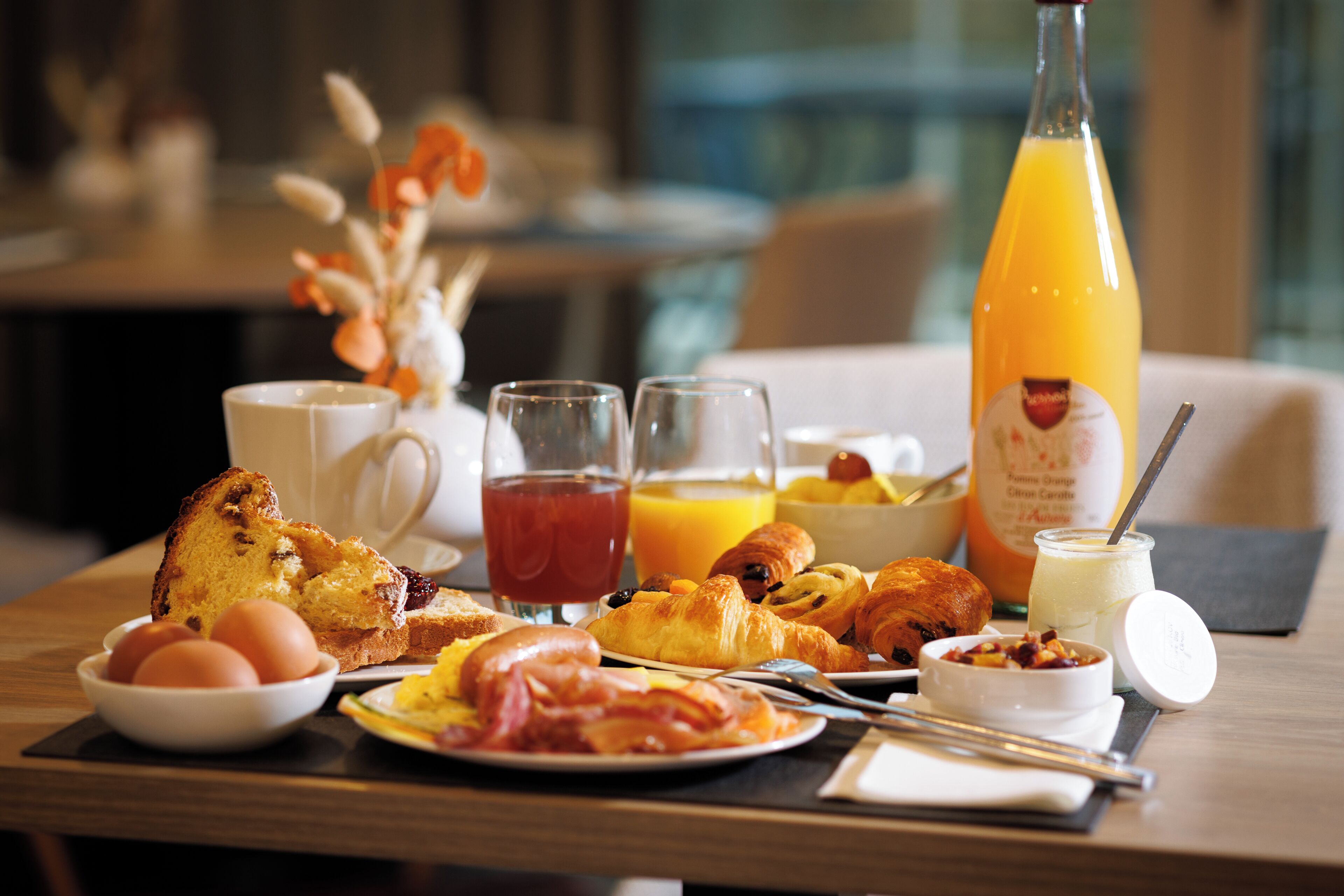 A breakfast table with croissants, eggs, toast, and orange juice.