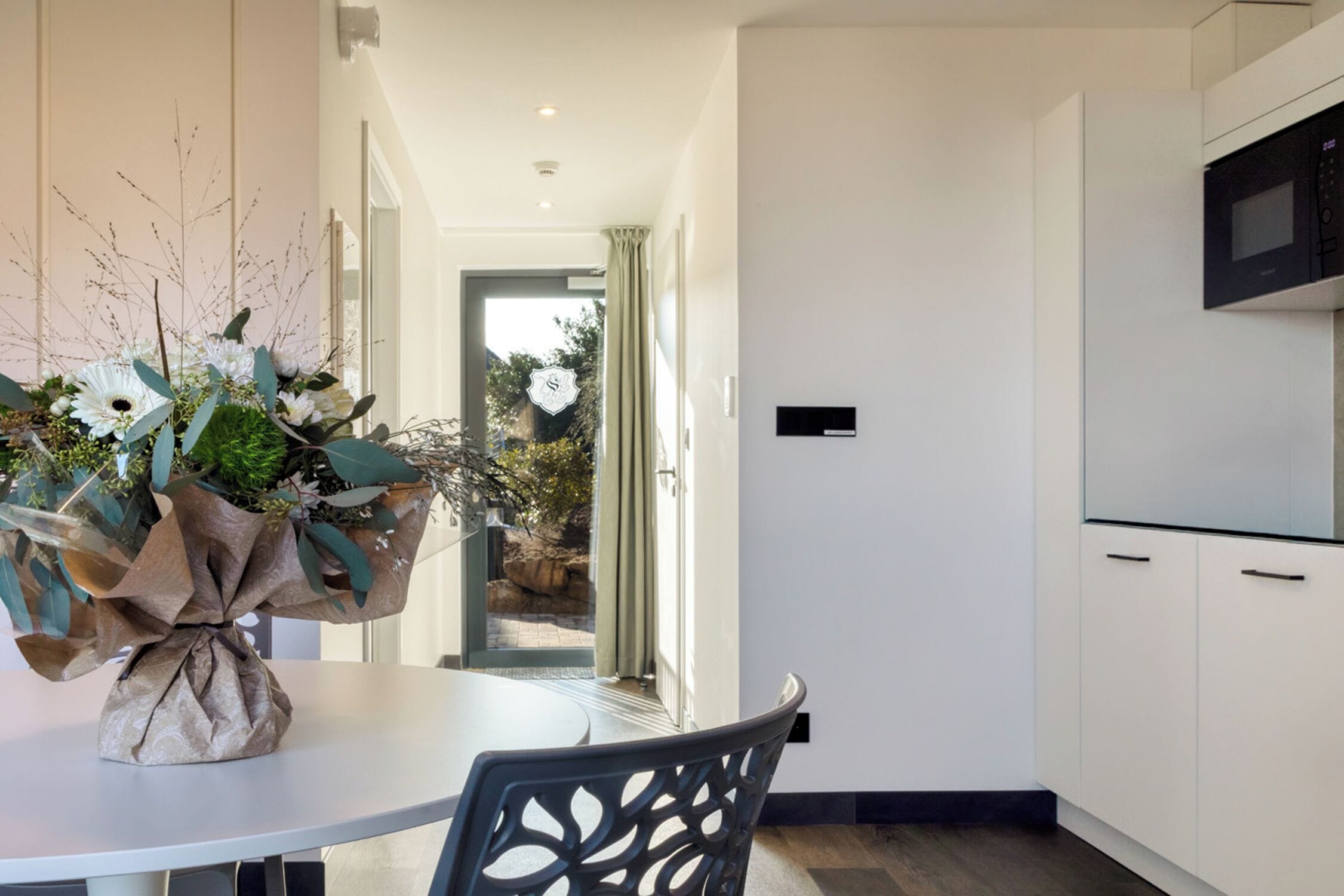 A modern kitchen with white cabinets, a microwave, and a dining area with a table and chairs.