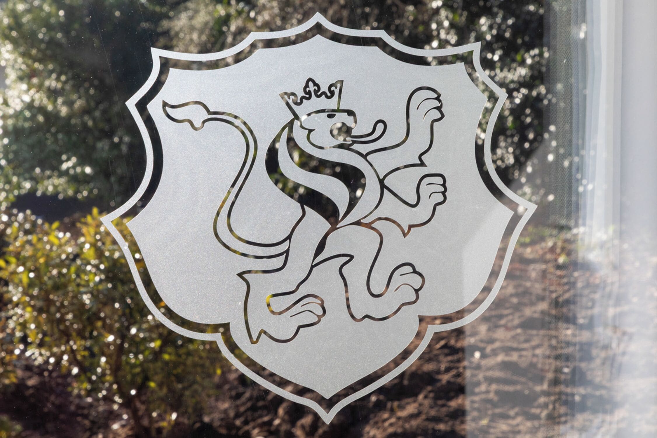 Un emblème en forme de bouclier, orné d’un lion et d’une couronne, qui pourrait être un logo ou un blason.