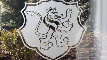 A shield-shaped emblem with a lion and crown, likely a logo or crest.
