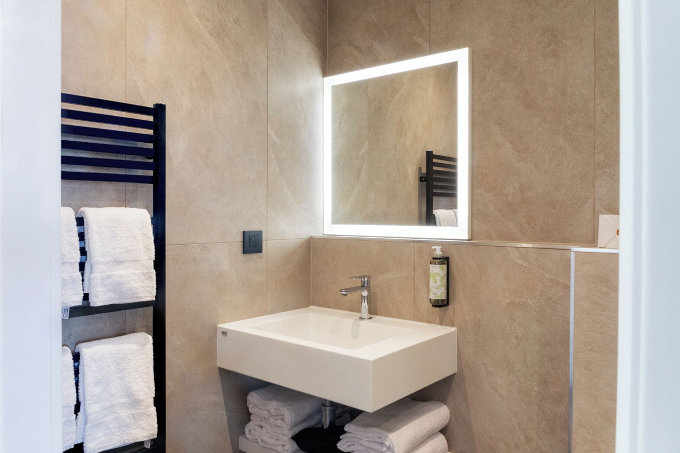Une salle de bain moderne avec un lavabo blanc, un miroir et un porte-serviettes.
