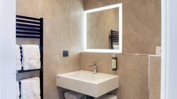 Une salle de bain moderne avec un lavabo blanc, un miroir et un porte-serviettes.