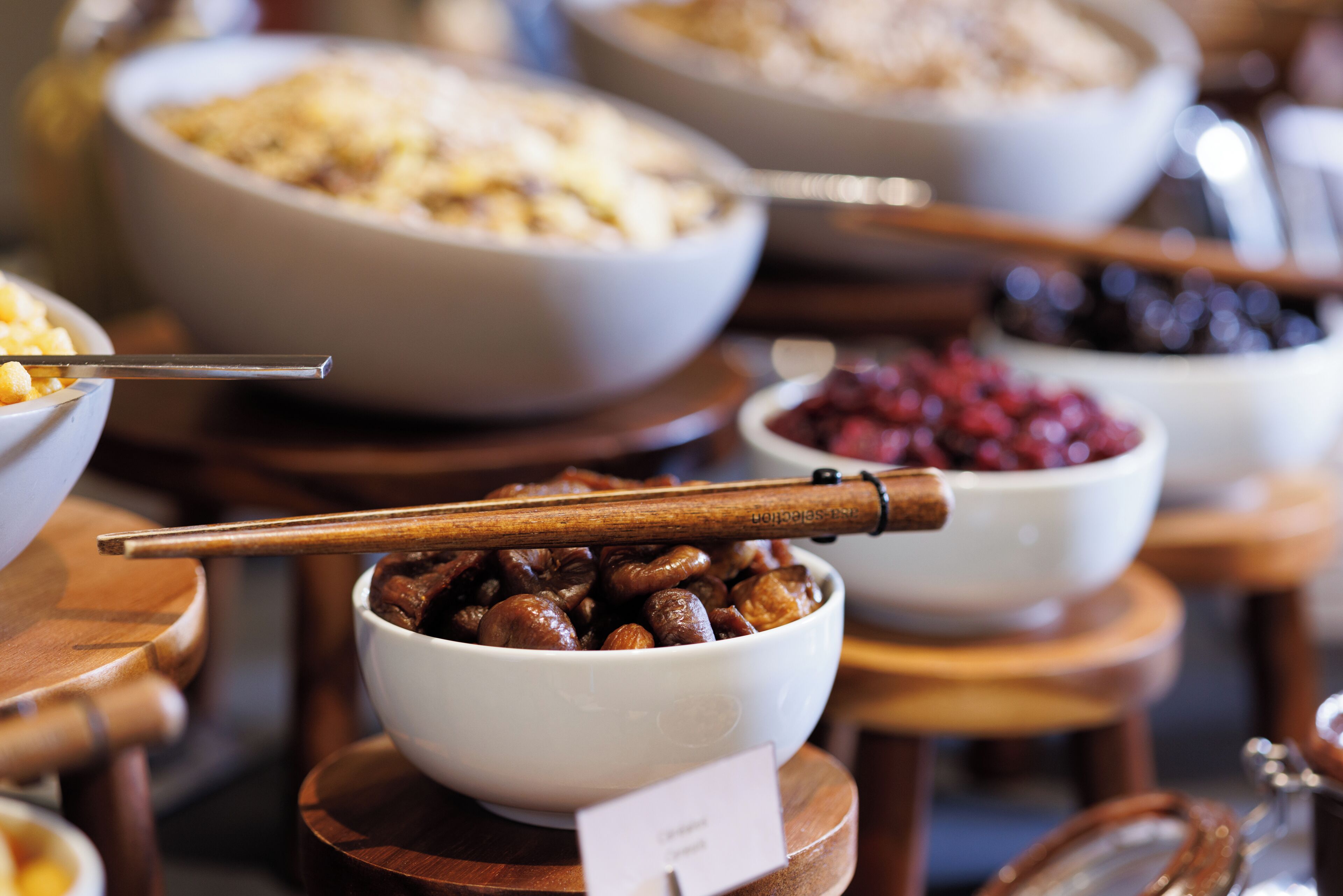 A variety of bowls with different foods, including a bowl of nuts, on wooden stands.