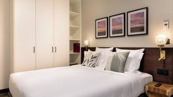 A neatly made bed with white linens, a wooden headboard, and three framed pictures on the wall.
