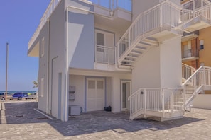 A multi-story building with balconies, a staircase, and a door leading to a garage.