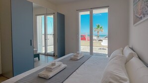 A hotel room with a bed, a large window, and a view of the beach. - Seafront & Reserved Parking (Civitanova Marche)