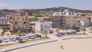 A coastal residential area with multi-story buildings, a parking lot, and a beach in the foreground. - Seafront & Reserved Parking (Civitanova Marche)