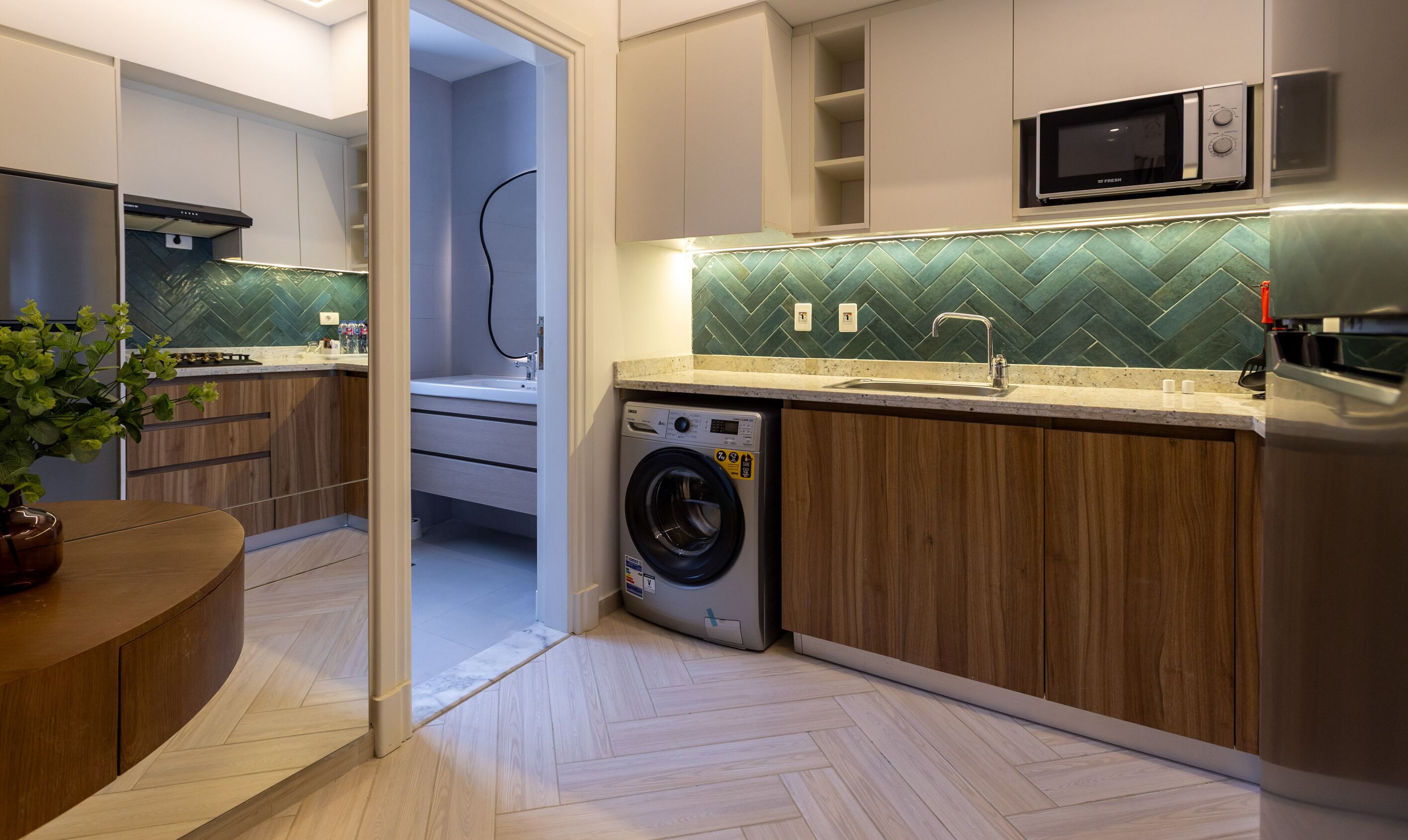 Eine moderne Küche mit integriertem Waschtrockner, einer Mikrowelle und einer Spritzschutzwand mit Fischgrätenmuster.