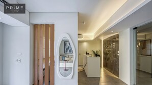 A modern hotel lobby with a reception desk, a large mirror, and a seating area with a sofa and a small table. - Prime Residence Zayed Hills (Sheikh Zayed City)