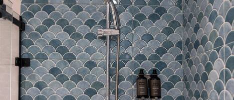 A bathroom with a shower head, a handheld shower attachment, and two bottles of shampoo and conditioner.