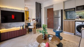 A modern living room with a TV, sofa, coffee table, and a dining area with chairs. - Prime Residence Zayed Hills (Sheikh Zayed City)