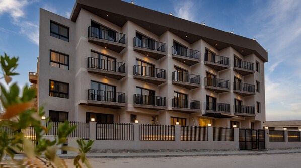 A multi-story hotel with balconies, a gated entrance, and a clear sky. - Prime Residence Zayed Hills (Sheikh Zayed City)