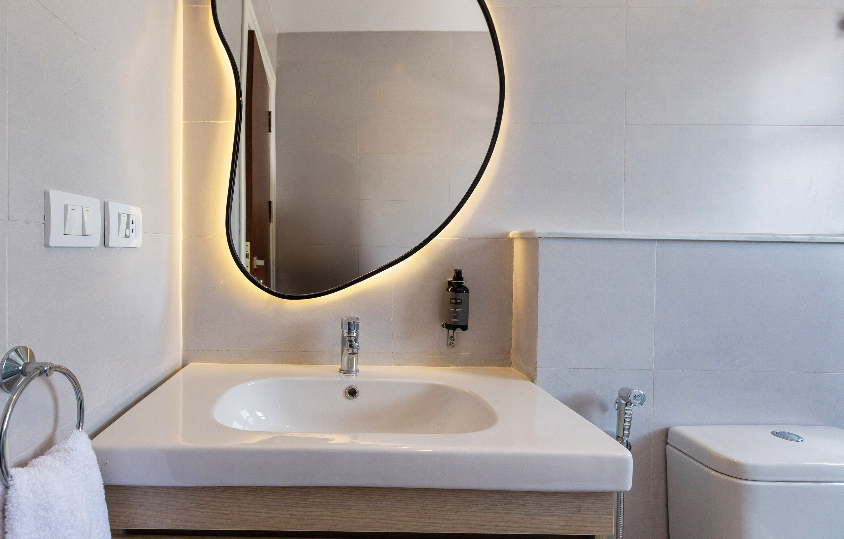 Une salle de bain moderne avec un lavabo blanc, un miroir à cadre noir et des toilettes.