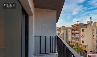 Un edificio residencial con balcón, cielo despejado y edificios de apartamentos vecinos.
