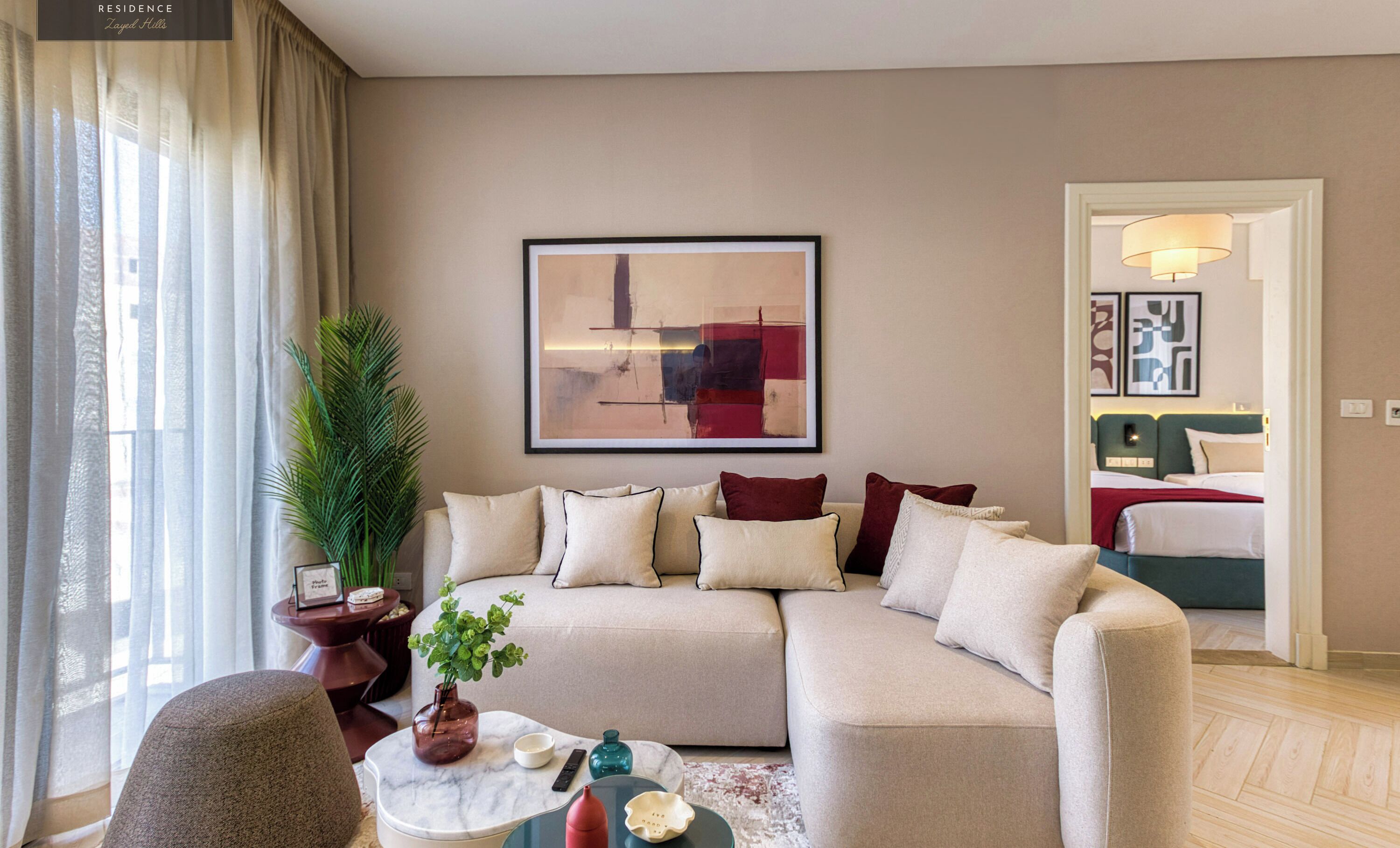 A modern living room with a beige sofa, a coffee table, and a large abstract painting on the wall.