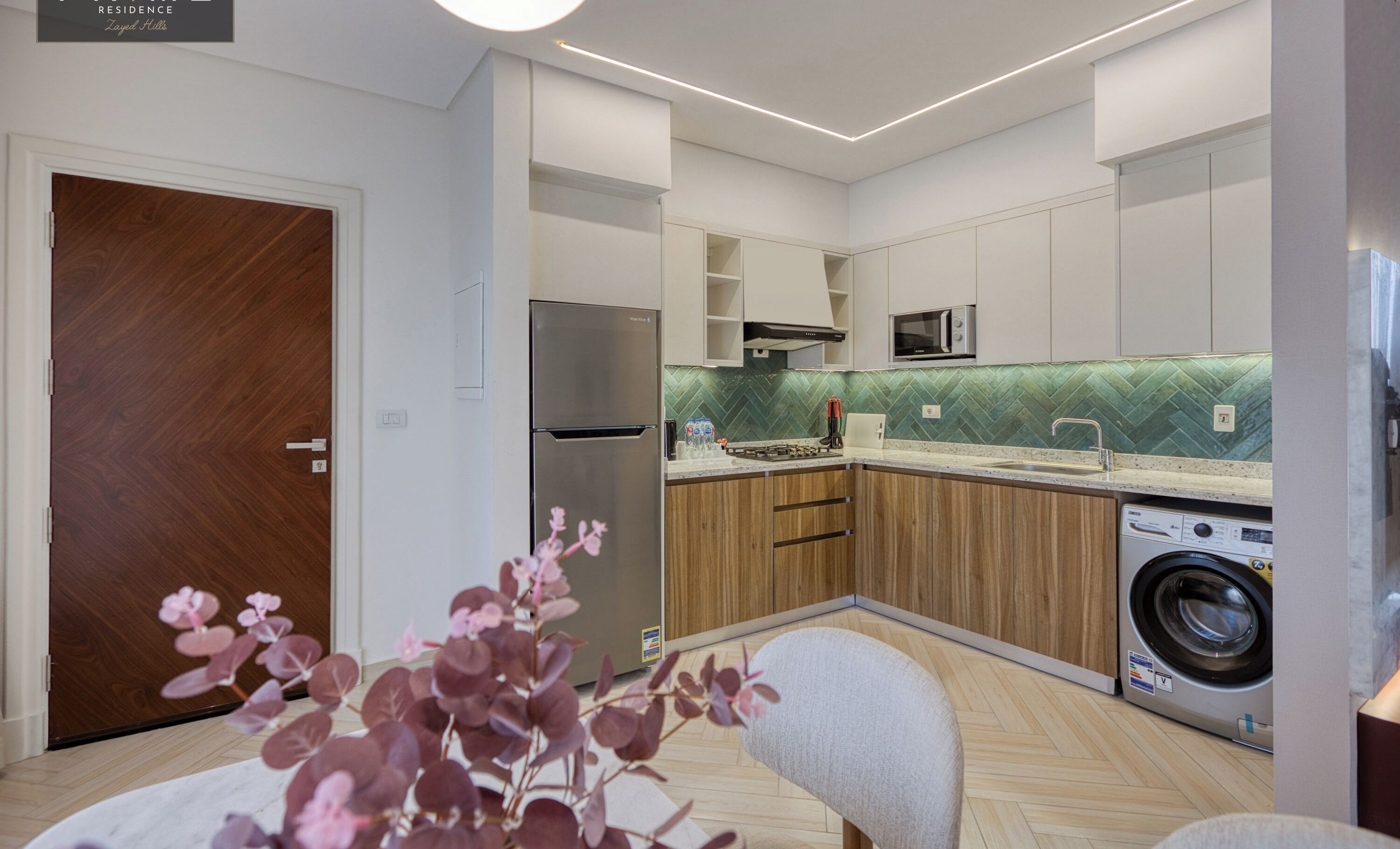 Een moderne keuken met een ingebouwde wasmachine, een koelkast en een magnetron.