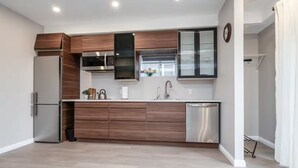 A modern kitchen with a built-in oven, microwave, and dishwasher. - The Simple Escape (Kitchener)