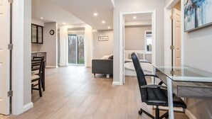 A spacious living area with a glass dining table, a sofa, and a bed. - The Simple Escape (Kitchener)